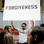 man holding up sign that says forgiveness