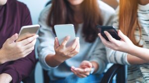 Group of young people using and looking at mobile phone while sitting together